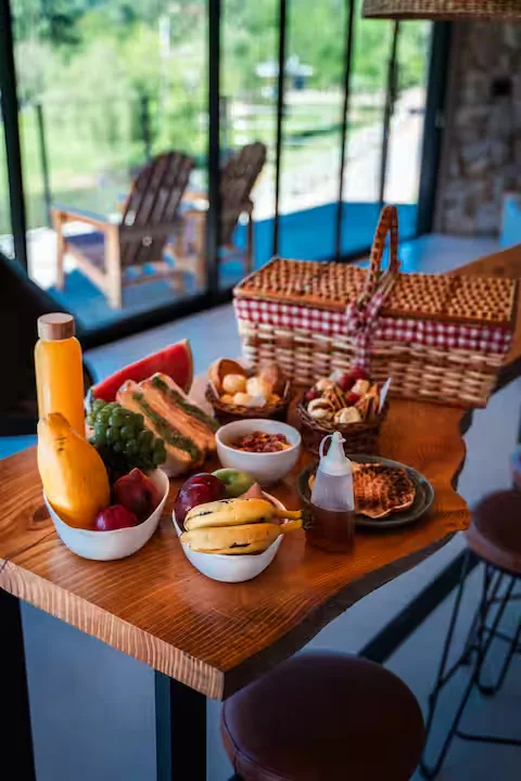 Cesta de café da manhã com frutas, pães e suco sobre a mesa