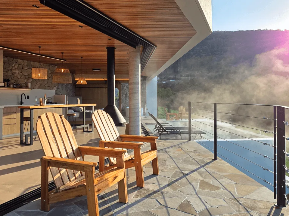 Deck com cadeiras de madeira e firepit diante da serra