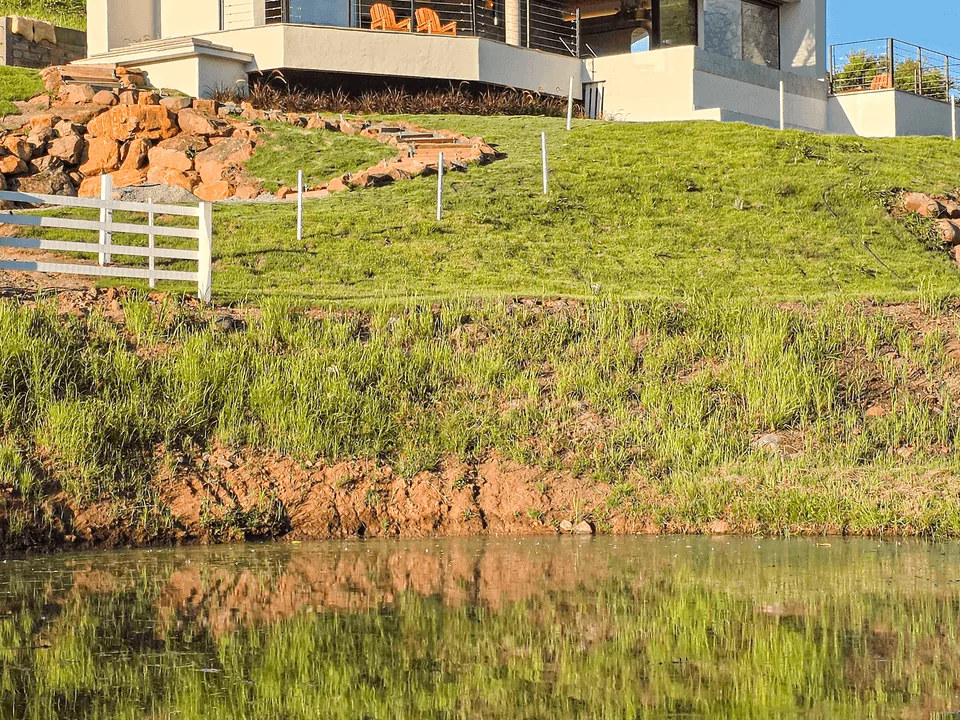 Lago ao lado do terreno da casa, com a casa ao alto